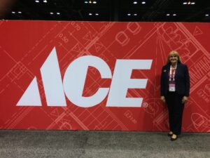 A woman standing in front of a large ace sign.