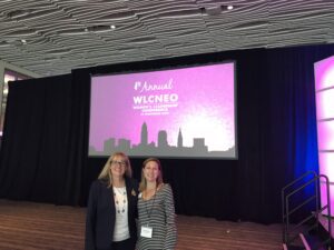 Two women standing in front of a projection screen.